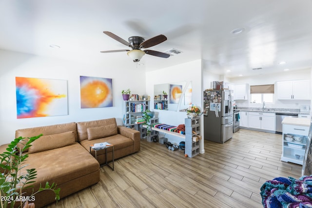 living room featuring light hardwood / wood-style floors, ceiling fan, and sink