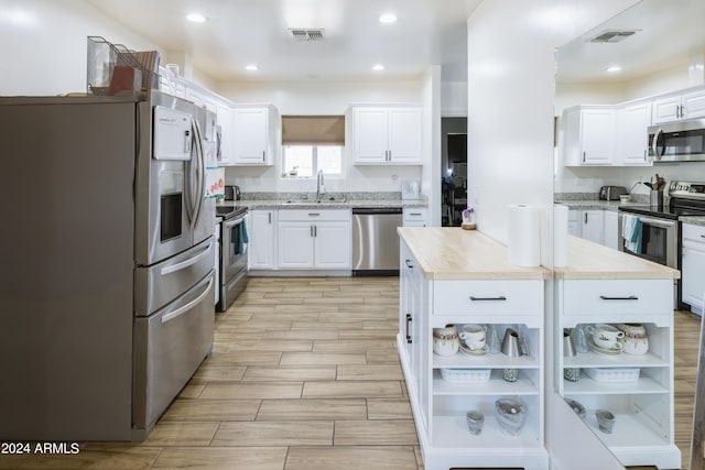 kitchen featuring appliances with stainless steel finishes, sink, light hardwood / wood-style flooring, white cabinetry, and butcher block counters