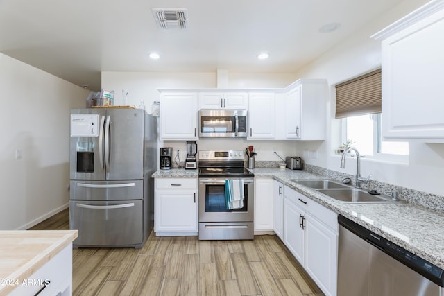 kitchen with white cabinetry, sink, light hardwood / wood-style floors, and appliances with stainless steel finishes