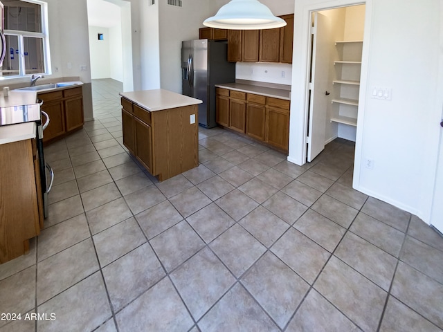 kitchen featuring decorative light fixtures, range, light tile patterned floors, stainless steel fridge with ice dispenser, and a center island