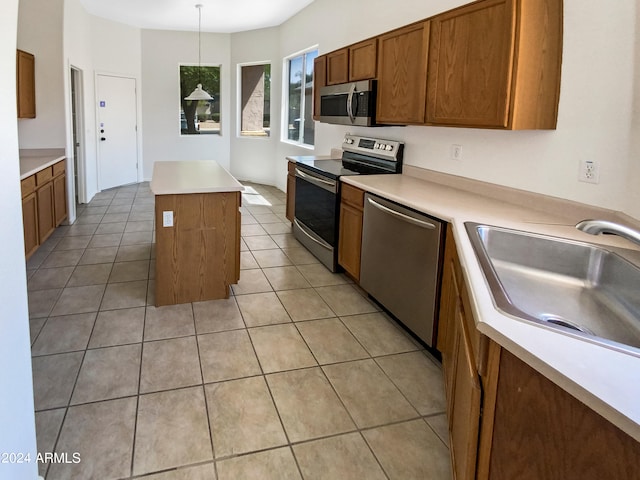 kitchen featuring light tile patterned floors, stainless steel appliances, a center island, sink, and hanging light fixtures