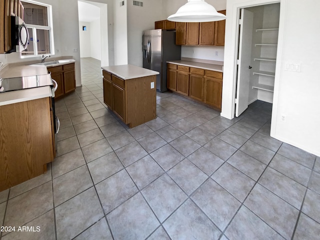 kitchen featuring light tile patterned floors, a kitchen island, stainless steel appliances, and pendant lighting