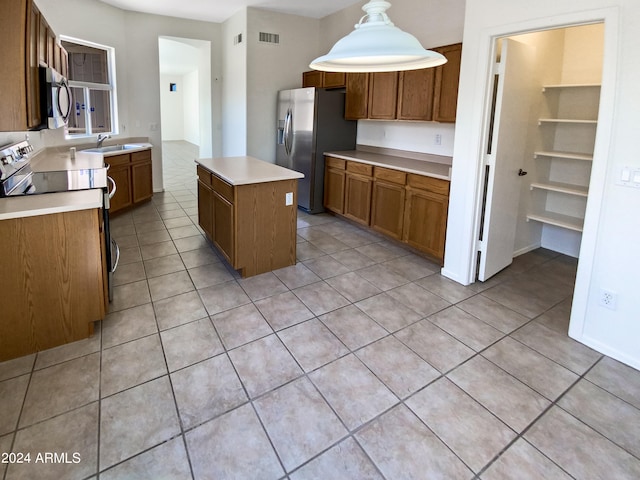 kitchen featuring pendant lighting, sink, a center island, appliances with stainless steel finishes, and light tile patterned flooring