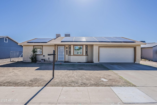 ranch-style home featuring stucco siding, a garage, driveway, and solar panels