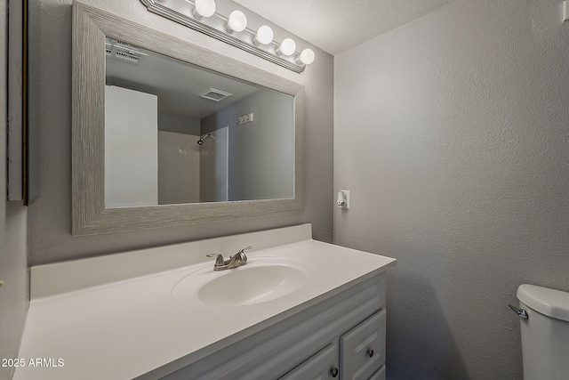 bathroom featuring vanity, toilet, and a textured wall