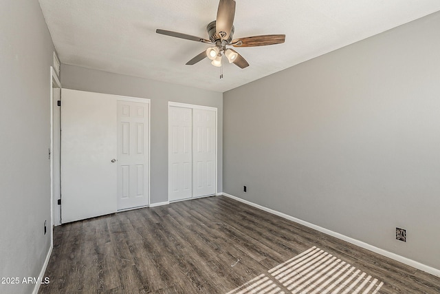 unfurnished bedroom featuring dark wood-style floors, baseboards, and a closet