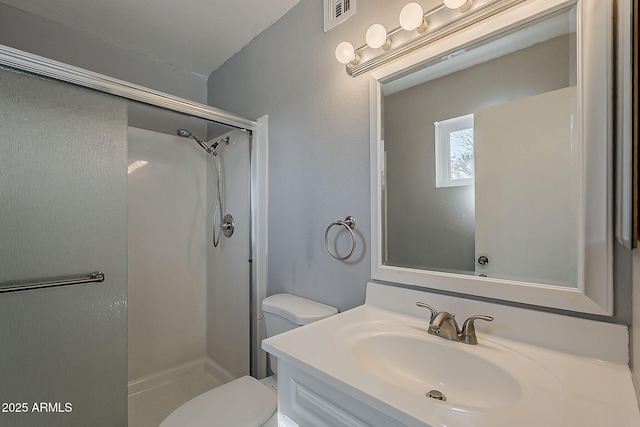 bathroom with a stall shower, toilet, and vanity
