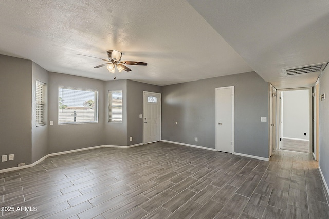 foyer entrance featuring ceiling fan, baseboards, dark wood-type flooring, and a textured ceiling
