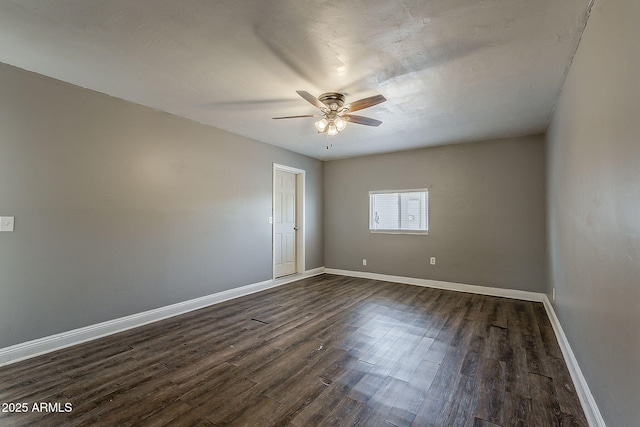 spare room with a ceiling fan, dark wood-style floors, and baseboards