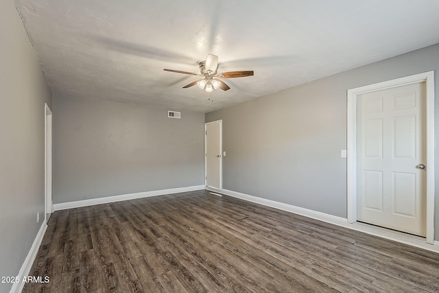 spare room with dark wood-style flooring, ceiling fan, and baseboards