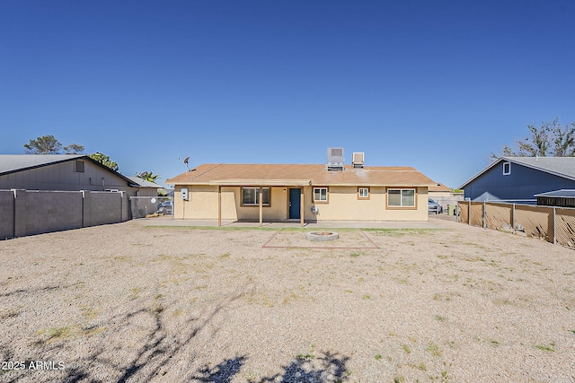 rear view of property featuring an outdoor fire pit, a fenced backyard, a patio area, and stucco siding