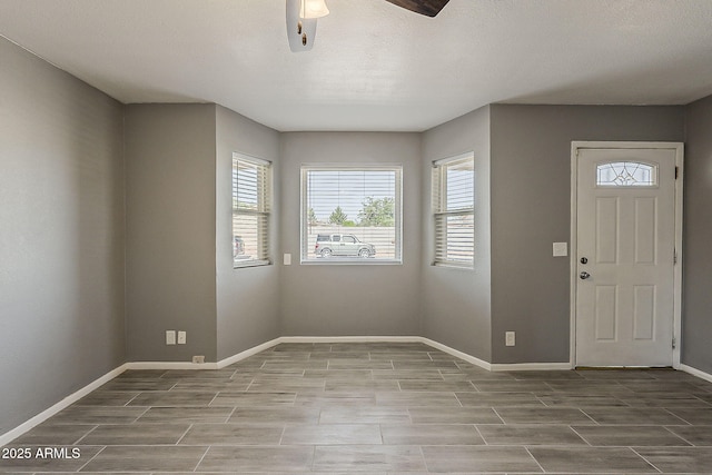 entrance foyer with healthy amount of natural light, a ceiling fan, and baseboards