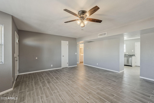 unfurnished living room featuring ceiling fan, wood finished floors, and baseboards
