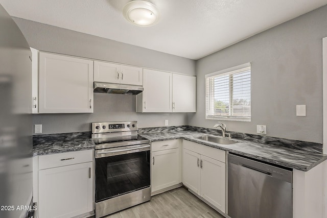 kitchen featuring stainless steel appliances, a sink, under cabinet range hood, light wood-type flooring, and white cabinetry
