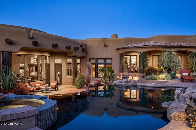 pool at dusk with a patio area, an in ground hot tub, and an outdoor fire pit