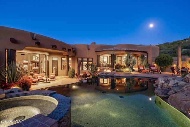 pool at dusk featuring a patio area and an in ground hot tub