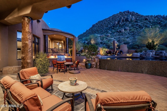 patio terrace at dusk with a mountain view and area for grilling