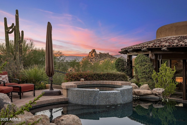 patio terrace at dusk featuring an in ground hot tub