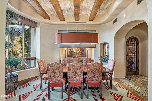 dining room with plenty of natural light, a towering ceiling, and beam ceiling