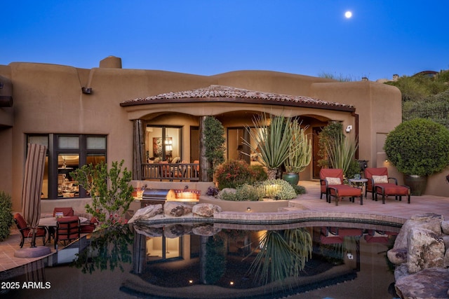 back house at dusk featuring a patio area