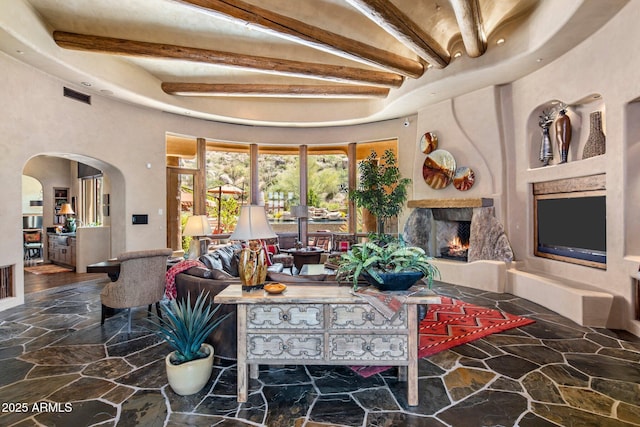 living room featuring a towering ceiling, a fireplace, and beamed ceiling