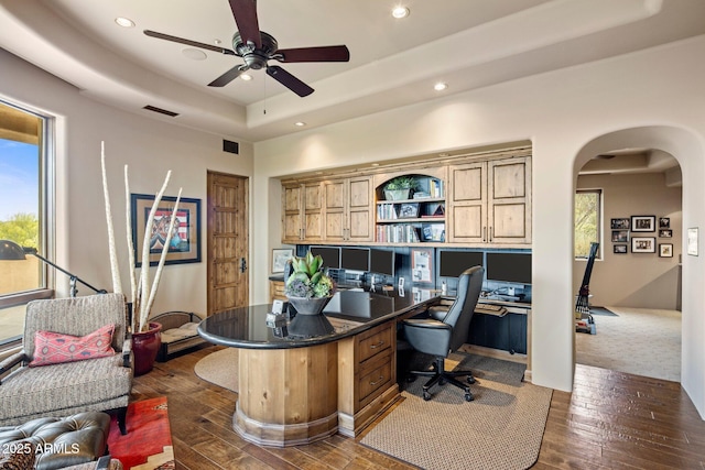 home office featuring a raised ceiling, ceiling fan, and dark hardwood / wood-style flooring