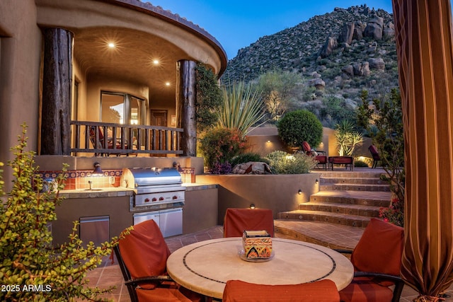 view of patio / terrace featuring an outdoor kitchen, grilling area, a mountain view, and sink