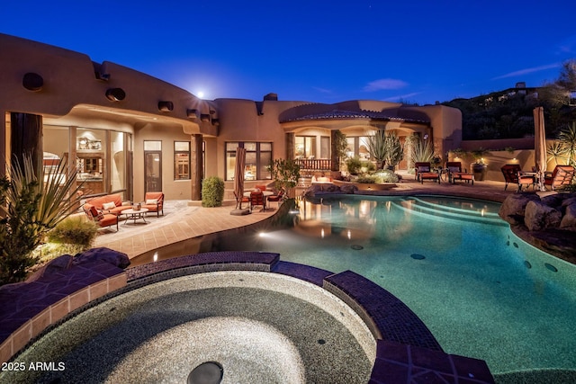 pool at dusk featuring an outdoor hot tub and a patio