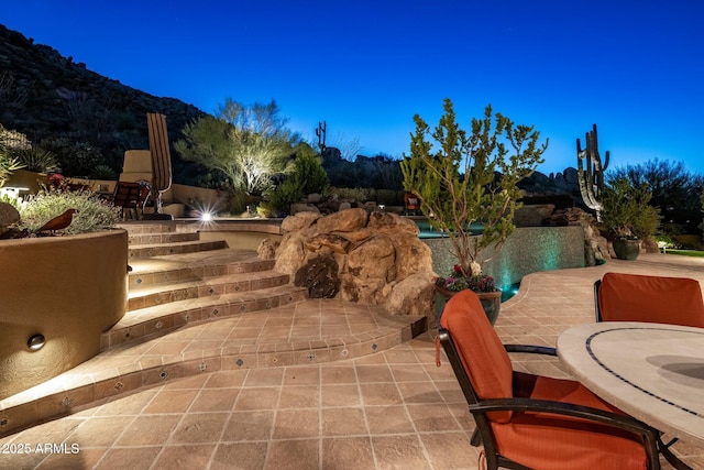 patio terrace at dusk featuring a mountain view