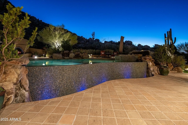 pool at dusk featuring a patio