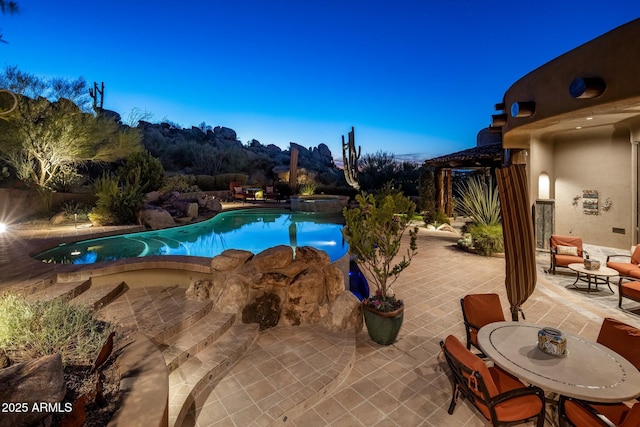 pool at dusk with a patio area