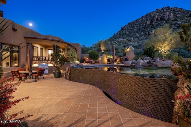 view of patio / terrace with a mountain view, a fireplace, a grill, and exterior kitchen