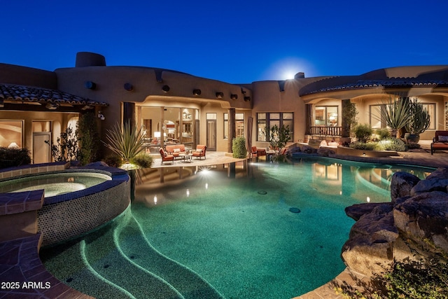 pool at night with an in ground hot tub and a patio