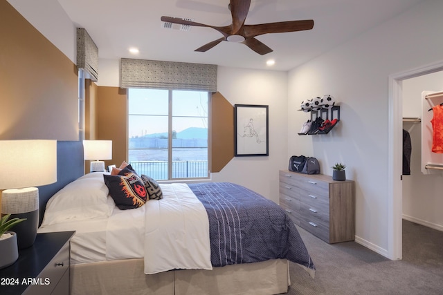 bedroom with carpet, ceiling fan, and a spacious closet