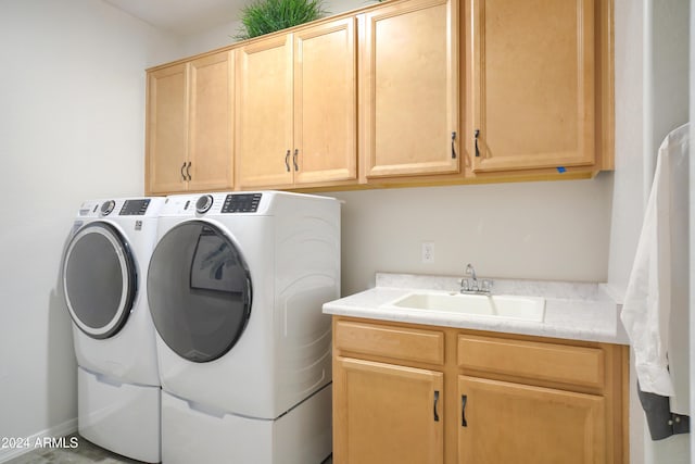 clothes washing area featuring cabinets, washer and clothes dryer, and sink