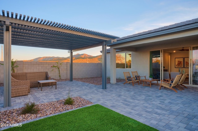 patio terrace at dusk with outdoor lounge area, a mountain view, and a pergola