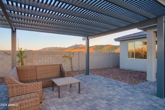 patio terrace at dusk featuring a mountain view, an outdoor living space, and a pergola