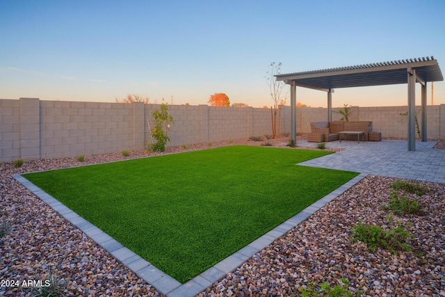 yard at dusk featuring an outdoor hangout area, a patio area, and a pergola