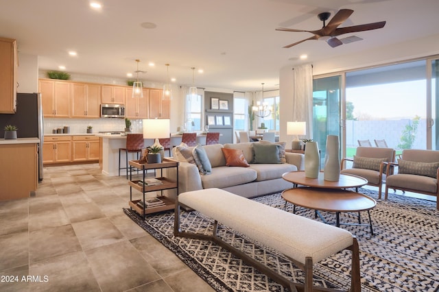 living room with ceiling fan with notable chandelier