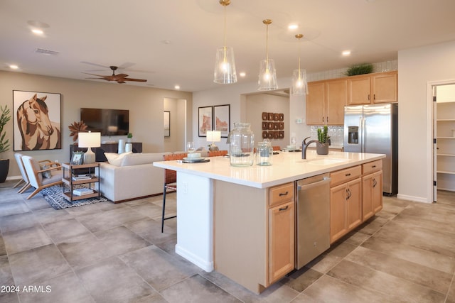 kitchen with sink, ceiling fan, an island with sink, appliances with stainless steel finishes, and light brown cabinetry