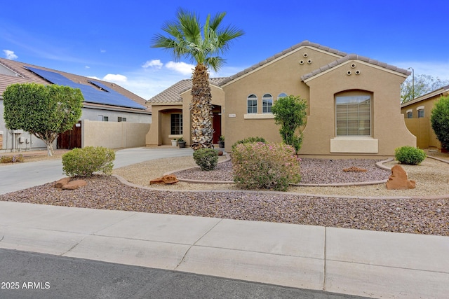 view of front of property featuring driveway, a tile roof, fence, and stucco siding