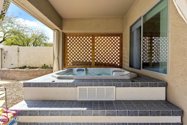 view of patio / terrace with visible vents, an outdoor hot tub, and fence