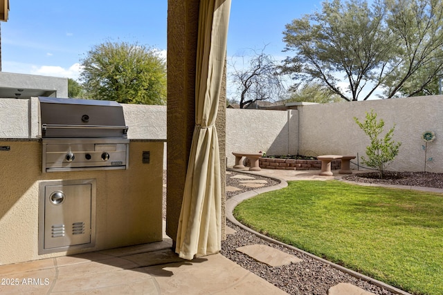 view of patio / terrace featuring a fenced backyard, a grill, and an outdoor kitchen