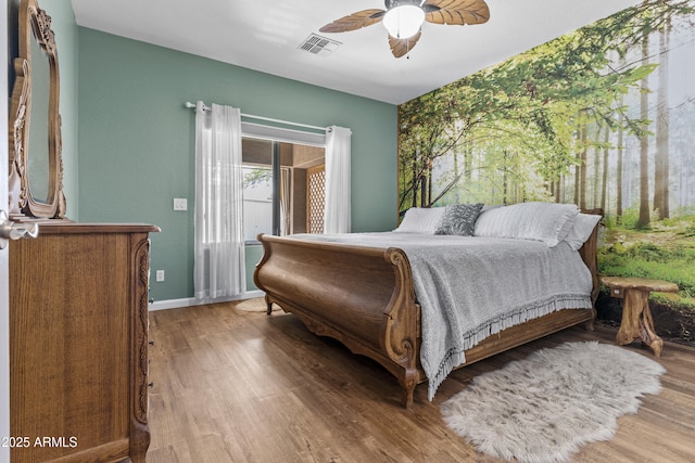 bedroom featuring baseboards, visible vents, ceiling fan, and wood finished floors