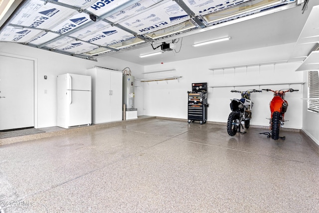 garage featuring water heater, a garage door opener, freestanding refrigerator, and baseboards