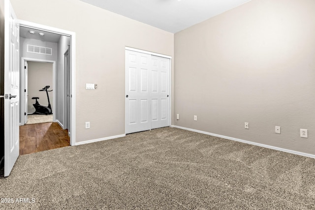 unfurnished bedroom with a closet, carpet, visible vents, and baseboards