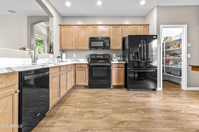 kitchen with light wood-style floors, light brown cabinets, light countertops, and black appliances