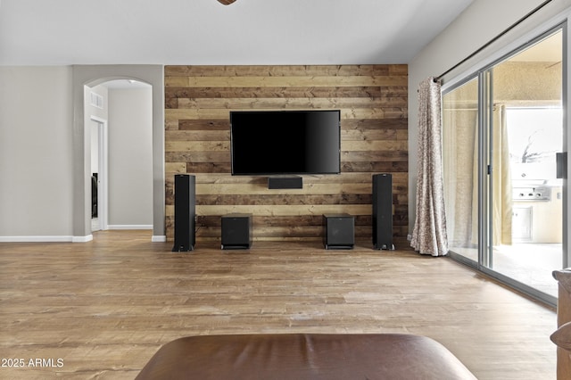 living room featuring a healthy amount of sunlight, light wood-style flooring, and wooden walls