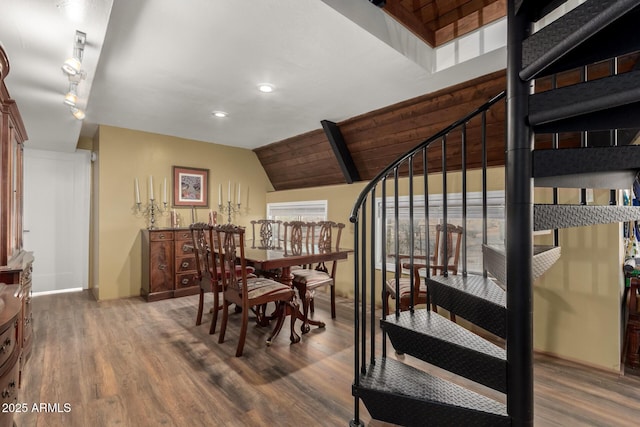 dining area featuring a healthy amount of sunlight, stairs, wood finished floors, and lofted ceiling