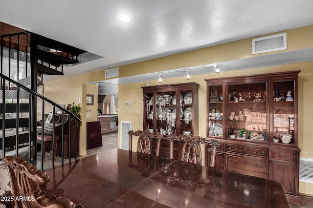 dining area with stairs, visible vents, and wood finished floors